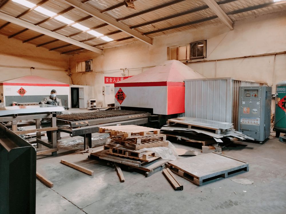 CNC laser cutter processing steel sheet for vending machine body panels at KioskForce manufacturing facility